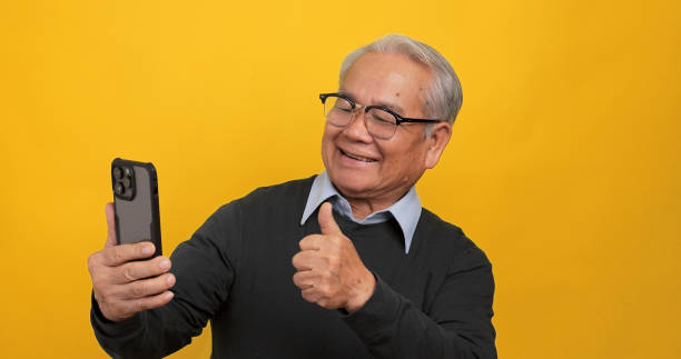 istock Asian old man using smart phone. Isolated on yellow background in the studio. 1969207501