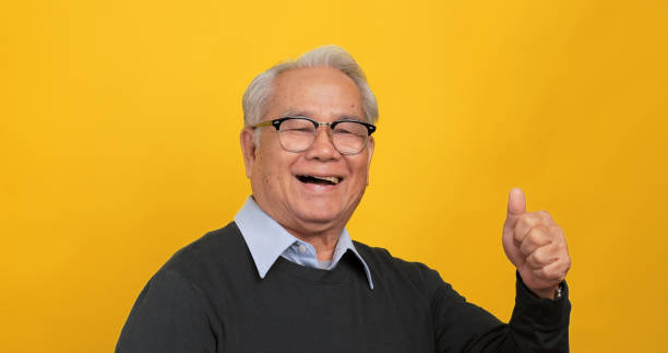 istock An old Asian man is showing approval for something. Isolated on yellow background in the studio 1969207508