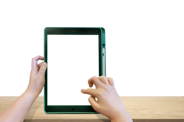 Boy's hands holding a tablet on a wooden table, white background
