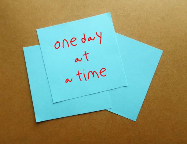 istock Blue notes on office envelope with handwritten text ONE DAY A TIME, concept of dealing with each day problems as they come, less worry about future or expect things to change overnight 1969268748