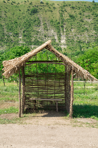 Covered bench under reed roof, picnic bower on a summer day with mountain background