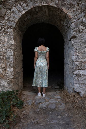 Young brunette woman visiting the old medieval fortress in Parga city, Greece.