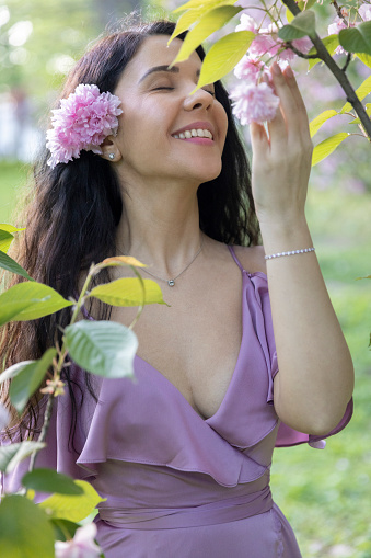 Lovely young woman admiring the blossom flowers from a tree.