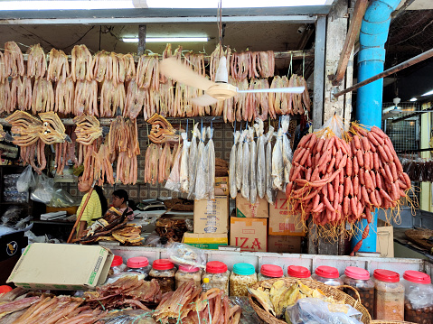 Local lady with kid at her stall selling dried fish and pork sausages in Psah Chas (Old Market), also commonly romanized as Phsar Chas, Psar Chas or Psar Chaa, a popular market in Siem Reap, Cambodia.