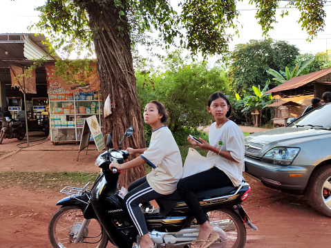 Two local girls riding a motorcycle in Kampong Phluk, a commune in Prasat Bakong District in Siem Reap Province Cambodia.