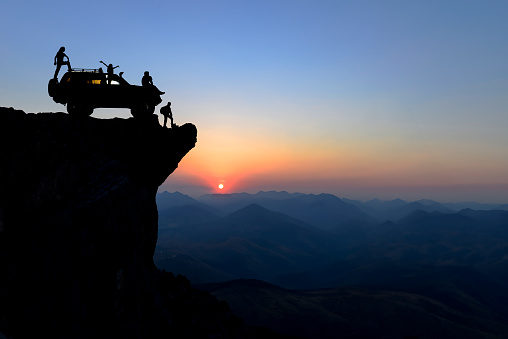 Adventurous group watching the view with an all-terrain vehicle on the cliff