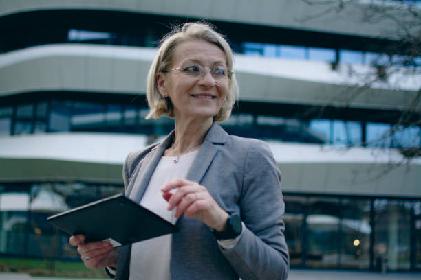 istock mature blonde business woman using tablet while standing outside 1969339986
