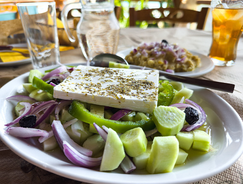 feta cheese cut in cubes, vegetables, herbs and olive oil-the ingredients for a greek salad