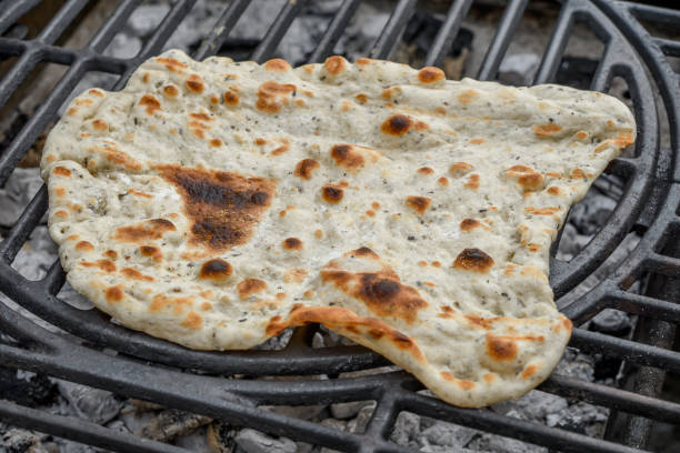 Grilled crispy flatbread lies on the grill grate closeup isolated