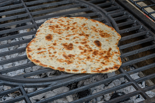 Grilled crispy flatbread lies on the grill grate closeup isolated