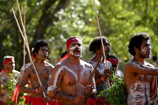 Laura, Qld - July 08 2023:Indigenous Australian men holding traditional weapons during a ceremonial dance in Laura Quinkan Dance Festival Cape York Australia. Ceremonies combine dance, song, rituals, body decorations and costumes