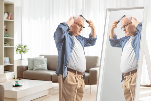 istock Mature man combing hair in front of a mirror at home 1969384236