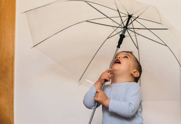 funny baby playing with a umbrella at home - sorter - fotografias e filmes do acervo