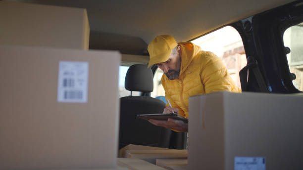 istock Courier with tablet checks postal parcels for delivery. 1969399912