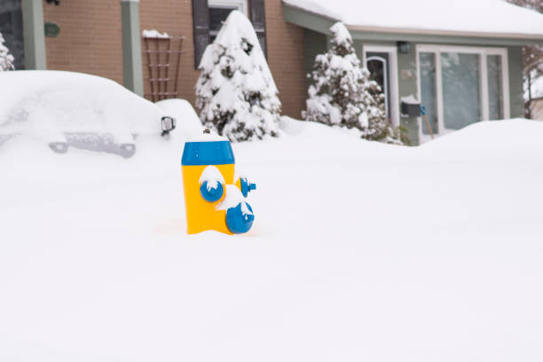 Fire hydrant and car are buried in cold piles of snow in a suburban neighborhood during the day after an extreme weather winter snow storm in Canada.
