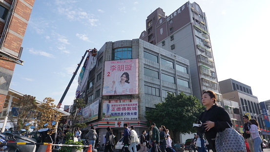 Kuomintang, Taiwan - January 27 2024:  unidentified workrer remove the banner on the building.  street view of Kuomintang, Kuomintang is the main city of southern taiwan
