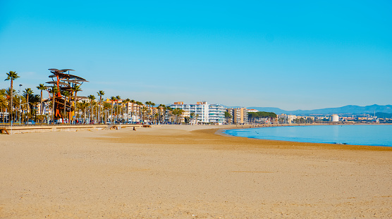 Vilaseca, Spain - December 26, 2023: A view of La Pineda beach and its promenade, in Vilaseca, Spain, on a sunny winter day. La Pineda is a coastal resort on the Mediterranean sea popular with locals