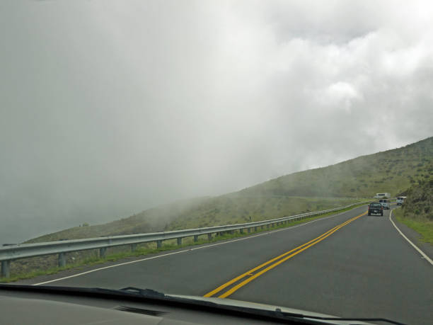 carros dirigindo por estrada de montanha ventosa com nuvens baixas - haleakala national park mountain winding road road - fotografias e filmes do acervo