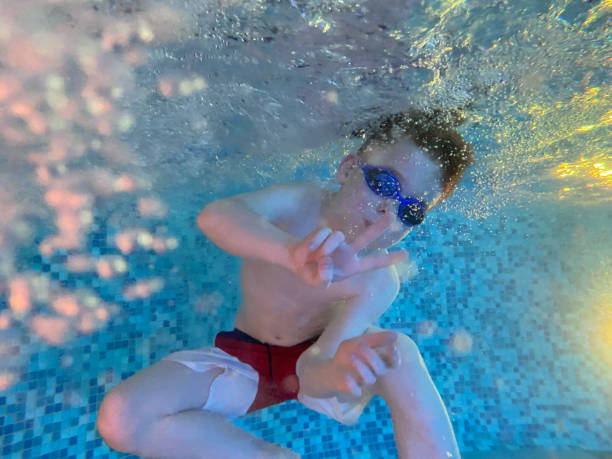 um menino mostrando sinal de paz ou vitória debaixo d'água na piscina - mobilestock freedom enjoyment blue - fotografias e filmes do acervo
