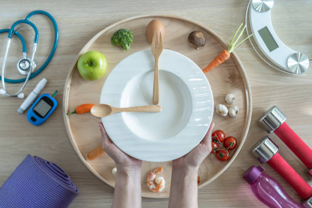 istock Intermittent fasting IF diet concept with hour clock timer for skipping meal, eating keto low carb food meal healthy nutritional with gym exercise for weight loss, cholesterol and diabetic control 1969441865