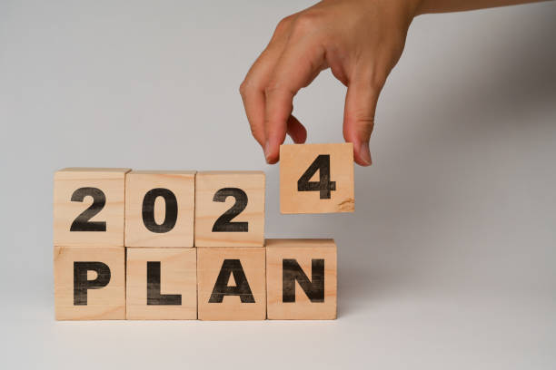 istock Hand placing wooden cube blocks with 2024 PLAN text on white background. Business vision and development concept 1969442934