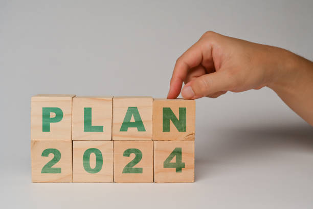 istock Hand touching wooden cube blocks with 2024 PLAN text. Business vision and development concept 1969442937