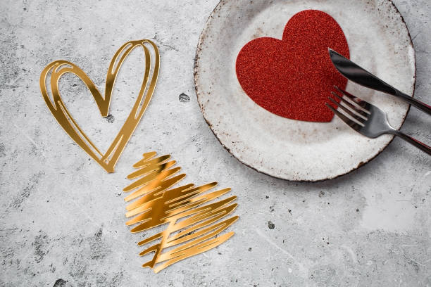 istock The banner. Table setting. Stylish ceramic plate and gold, red hearts on a concrete background. The concept of celebrating Valentine's Day for cafes and restaurants. 1969442946