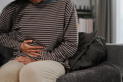 Unhappy young woman holding belly suffering from abdominal pain, digestive problems. Health care concept.