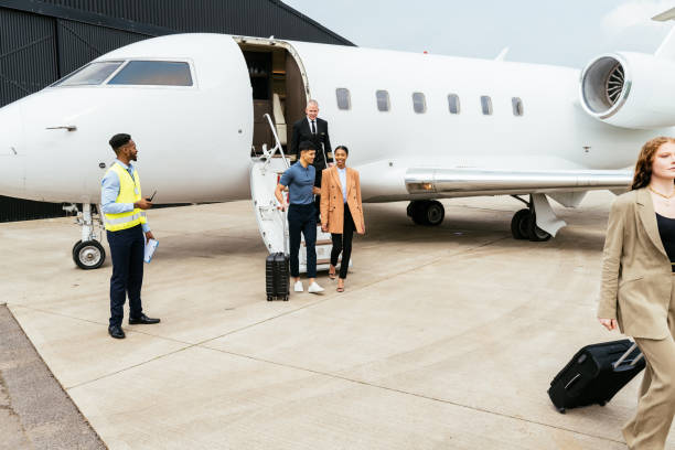 istock Passengers boarding in private luxury jet near hangar, pilot welcomes the young successful passengers 1969467853