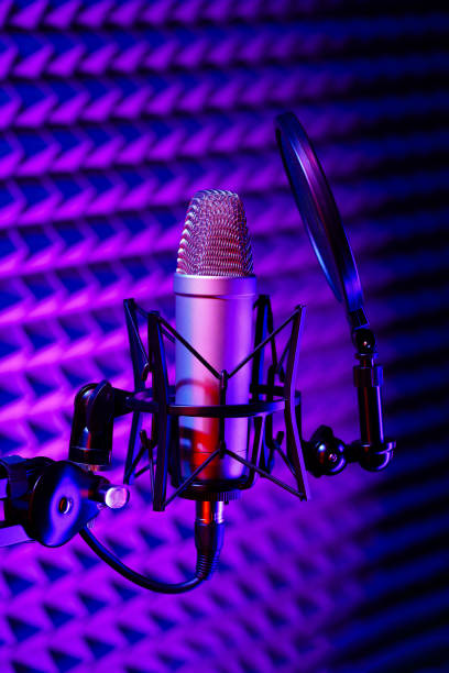istock Professional studio microphone against acoustic foam panel background in neon light 1969472671