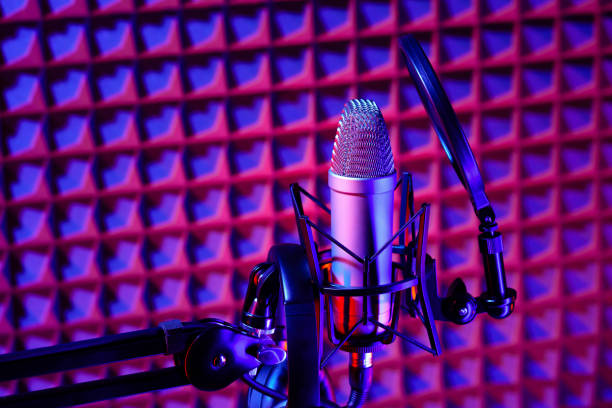 istock Professional studio microphone against acoustic foam panel background in neon light 1969473192