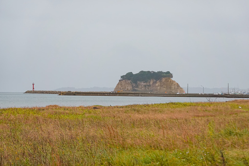 On a cloudy day in October 2023, Mitsuke Island seen from the Ukai fishing port over the embankment at Ukai, Hodatecho, Suzu City, Ishikawa Prefecture, Noto Peninsula.