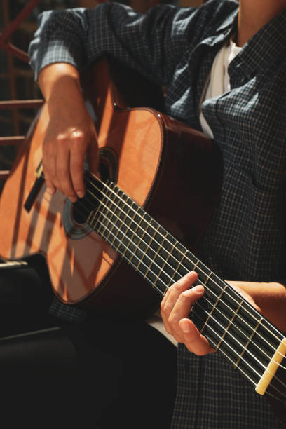 istock Woman in shirt playing on classical guitar 1969490128