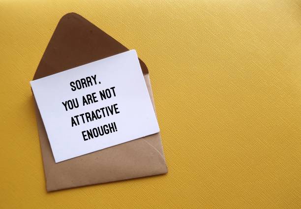 istock On copy space yellow background, envelope with note written SORRY, YOU ARE NOT ATTRACTIVE ENOUGH - concept of LOOKISM - discrimination treatment of people who are considered physically unattractive 1969492781