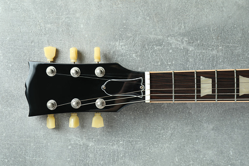 Top of electric guitar on gray textured background