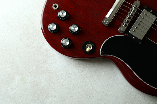 Electric guitar on white textured background, space for text