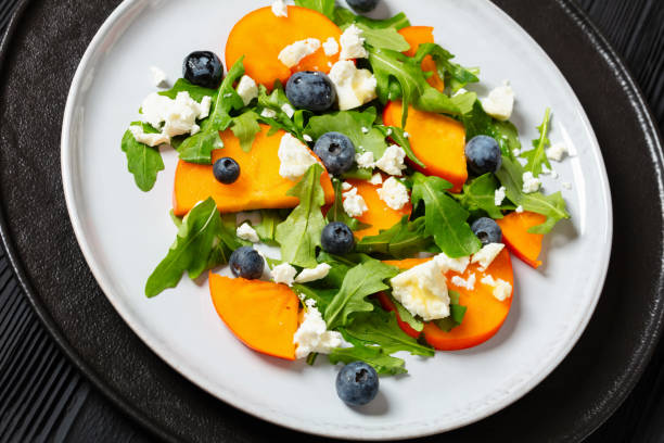 istock arugula persimmon cheese berries salad, top view 1969536050