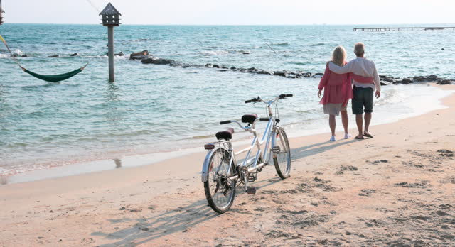 Couple take tandem bicycle to beach, water's edge