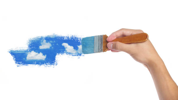 istock Hand with paintbrush painting sky isolated on white background 1969554994