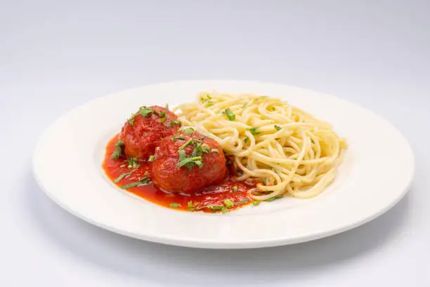 Photo of Business lunch. Meat balls in tomato sauce with spaghetti on a white background