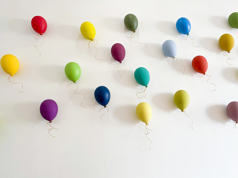 Colorful balloons flying on a white wall