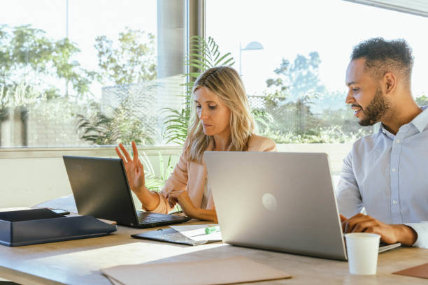 istock Two business people working on their laptops while sitting on a desk at the office. 1969614270