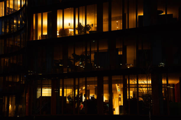 Office building exterior with glowing lights in windows at night city. Vienna city downtown district with skyscraper facades. Night city panorama. Working late at corporation