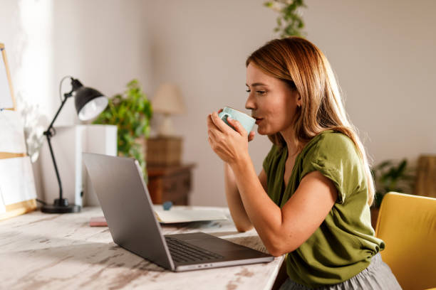 istock Woman sipping coffee while working at her desk 1969628116