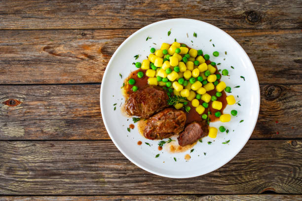 baked pork cheeks in sauce with gnocchi and green peas on wooden table - steak plate gourmet beef imagens e fotografias de stock