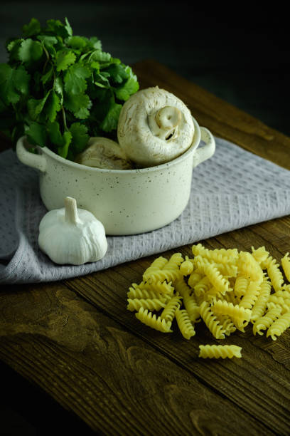 istock Raw macaroni and greens with mushrooms in bowl on towel on table 1969669375