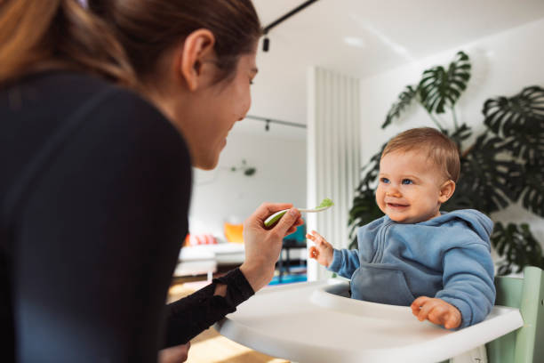 istock Mother feeds baby from spoon in modern house 1969670431