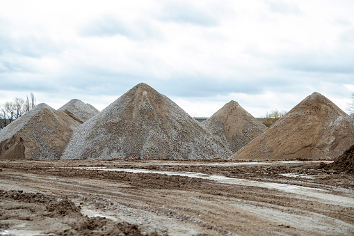Bulk material consisting of rock with different grain sizes lies on piles in a storage area for construction work.