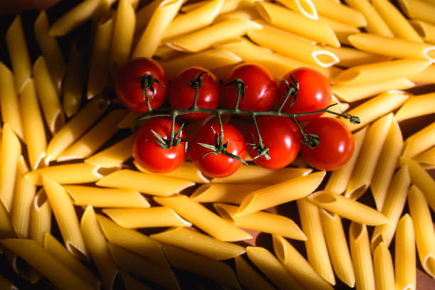 Top view of raw cherry tomatoes and macaroni with sunlight