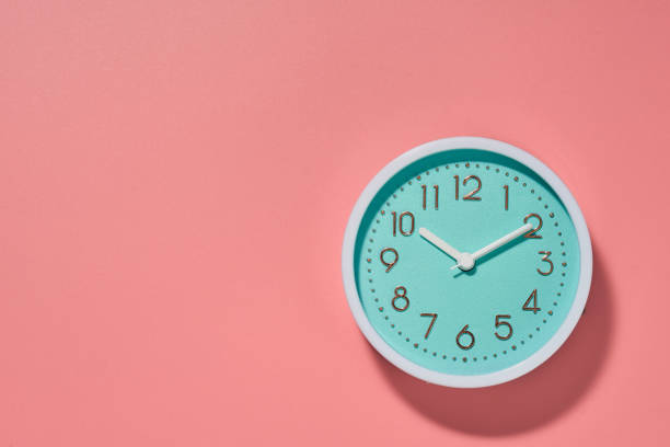 istock Round turquoise alarm clock on a pink background. Copy space. Top view. 1969689208